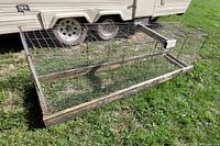 Full view of the chicken run showing metal wire panels and wooden base on grass.