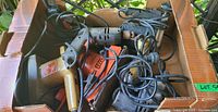 Photo showing box with tangled power tool cords and visible tool handles including a jigsaw and drills