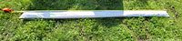 Full view of the 116-inch white mounting strip travel trailer awning laid on grass.