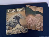 Photo showing two Japanese art books, one titled 'Hokusai: Paintings, Drawings and Woodcuts' and the other 'The Great Japan Exhibition: Art of the Edo Period 1600-1868'. The Hokusai book has a cover image of The Great Wave off Kanagawa. The Great Japan Exhibition book shows a scenic image with cherry blossoms.
