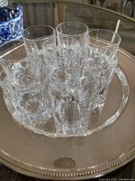 8 clear crystal shot glasses placed close together on a reflective surface with visible faceted cut pattern and no tray included.
