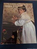 Cover photo of the Degas Exhibition art coffee table book. The cover shows a painting by Edgar Degas of a woman leaning on a table.