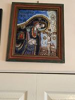 Framed painted glass icon depicting Virgin Mary and Crucifixion with inscriptions, blue and brown tones.
