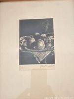 Full view of the monochrome woodblock print showing a still life with fruit and vessels, framed.