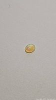 Natural Ethiopian opal oval cabochon laying on neutral background showing its size and color flashes.
