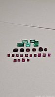 Photo of parcel showing oval and round blood red rubies beneath emeralds.