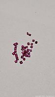 Parcel of loose square cut rubies scattered on a white surface, revealing vibrant red color and clarity.