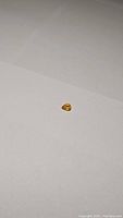 Photo of a small pear-shaped canary yellow sapphire gemstone on a plain surface, showing the deep golden yellow color and cut.