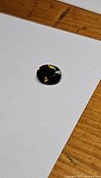 Close-up photo of an oval cut cognac orange tourmaline gemstone on white background with wooden surface visible.