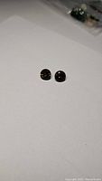 Two small round cut smokey quartz gemstones on a white background, showing size and shape.