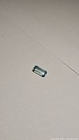 Close-up photo of the octagon cut blue zircon gemstone placed on a plain surface showing color and cut detail.