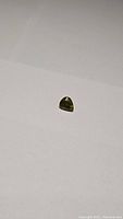Top-down view of a small pear-shaped deep moss green sphene gemstone on a plain background.