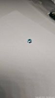 Single natural sky blue topaz gemstone on a white background, showing faceted round cut and bright blue color.