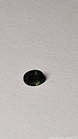 Forest green oval cut sapphire on a plain light surface.
