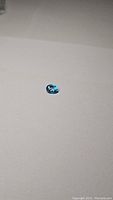 Photo showing the single natural Swiss blue topaz gemstone on a plain surface, displaying its color and cut shape.