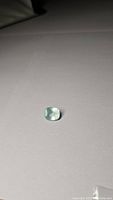 Image showing the aquamarine gemstone on a neutral background, highlighting its cushion cut and soft blue color.