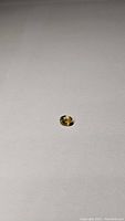 Close-up photo of oval cut yellow blue sapphire gemstone on a gray surface, showing top and angled views.