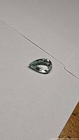 Pear-shaped aquamarine gemstone on white background showing full shape and clarity.