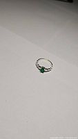 Ring positioned on a flat surface showing the full band and bright green onyx stone.