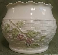 Photo of Belleek China planter showing basket weave texture and floral decoration with green leaves and pink flowers on white ceramic, scalloped rim detail.