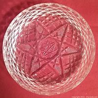 Top-down photo showing the six sided star design cut pattern on the Waterford crystal bottle coaster, placed on a red background.