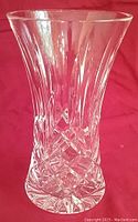 Clear Waterford Irish Crystal vase with the signature Lismore diamond and wedge cut pattern, photographed against a red background.