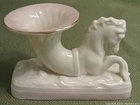 Porcelain seahorse shaped vase with pink interior and gold rim.