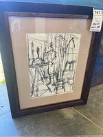 Framed black and white print with abstract interior and figure in dark wooden frame with beige mat.