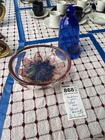 Photo showing both the glass bowl with internal star and petals design and the cobalt blue candle holder on a tablecloth.