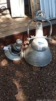 Top-down view of two metal industrial hanging light fixtures showing weathered surface and mounting hardware.
