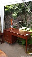 Front and right side view of desk showing three stacked drawers, central pencil drawer, and tapered legs