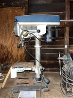 Full side view of Ryobi DP102L drill press showing base, column, motor, and spindle feed handles.