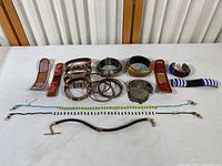Full view of the lot showing various bracelets and necklaces displayed on a white table surface under indoor lighting.