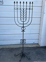 Full view of wrought iron floor standing candelabra, showing overall height, seven candle holders, and decorative scroll design.