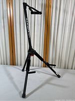 Full view of the black folding guitar stand with three legs and padded upper bracket