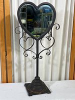 Full view of heart shaped mirror with decorative metal stand's front side.