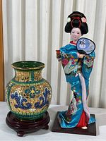Photo showing the Geisha doll next to the decorative vase on wooden stand; highlights size and appearance of both items.