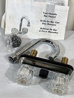 Two-handle bar faucet kit with instructions and box showing overall contents and condition.