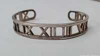 Front view of silver open cuff bracelet with Roman numeral cut-out design.