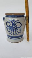 Front view of the blue and white terracotta pot with one handle and decorative swirl pattern, height shown by ruler.