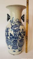 Front view of the porcelain vase with blue floral designs and ear handles, ruler included for size reference.