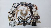 Full overview of costume jewelry lot showing necklaces, bracelets, earrings in multiple colors and styles laid out flat