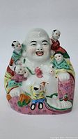Front view of the colorful porcelain Buddha statue surrounded by five children figures showing smiling Buddha face and detailed robes.
