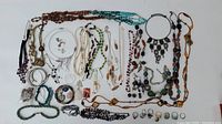 Wide view of the entire assortment of necklaces, bracelets, earrings, and pendants arranged flat showing variety and quantity in the lot.