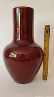 Porcelain red flambe vase next to ruler for size comparison showing approx. 7 inches tall
