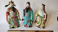 Front view of the three Chinese porcelain statues showing detailed robes and facial features.