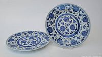 Two Chinese blue and white porcelain plates displayed to show front designs with floral patterns and vines.