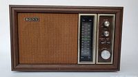 Front view of vintage Sony radio showing wood grain casing, speaker grille, tuning scale, and control knobs.