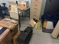 Overview showing microphone stand upright next to stacked Bose speakers and carrying bag in storage area