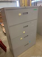Front view of the gray metal four drawer filing cabinet, showing drawer handles and locked drawers.